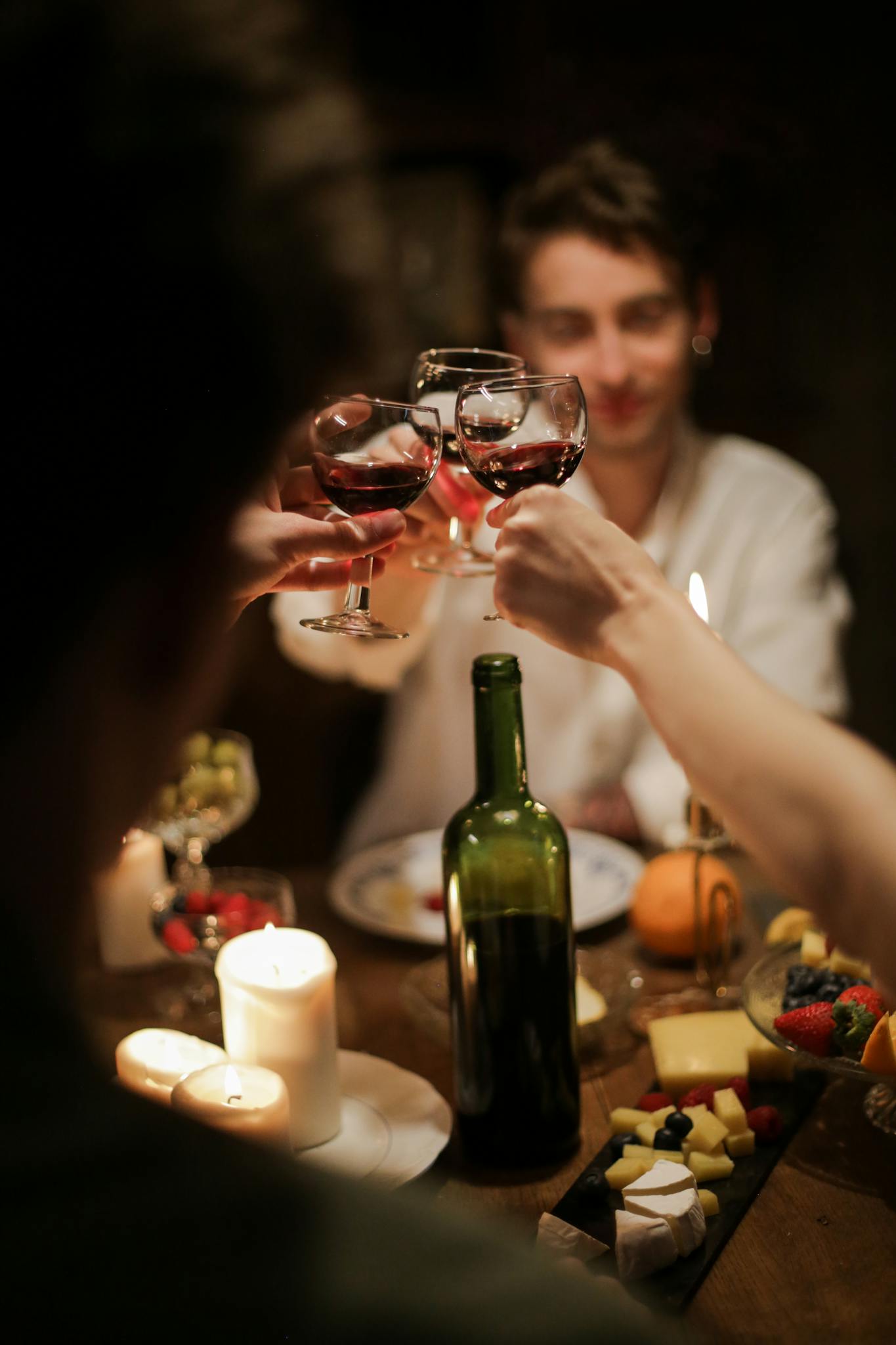 A warm and intimate dinner gathering with friends sharing wine and cheese by candlelight.